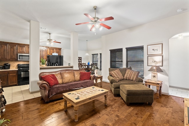 living area featuring visible vents, arched walkways, light wood-style floors, and ceiling fan