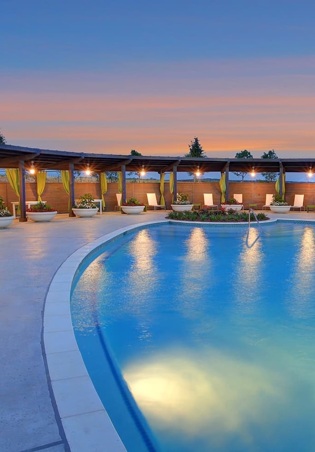 pool at dusk featuring fence, a fenced in pool, and a patio