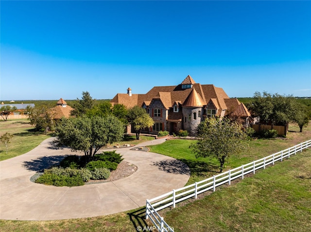 view of front of property featuring stone siding, curved driveway, fence, and a front yard