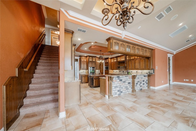 kitchen with visible vents, appliances with stainless steel finishes, brown cabinets, a tray ceiling, and a chandelier