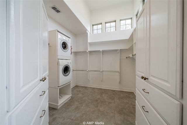 clothes washing area featuring stacked washer and dryer, laundry area, and visible vents