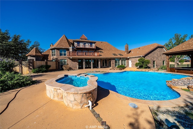 view of pool featuring a pool with connected hot tub, a patio, and fence