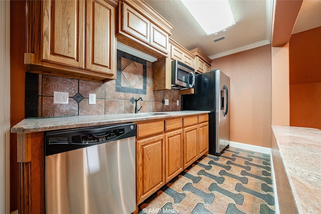 kitchen with appliances with stainless steel finishes, a sink, light countertops, crown molding, and backsplash