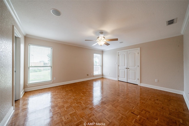 empty room featuring a textured ceiling, ornamental molding, visible vents, and baseboards