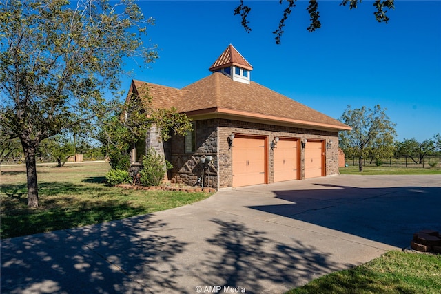 view of property exterior with driveway, roof with shingles, an attached garage, a yard, and brick siding