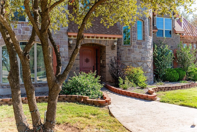 view of front of property featuring a shingled roof and stone siding