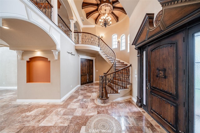 entrance foyer with arched walkways, a towering ceiling, decorative columns, and baseboards