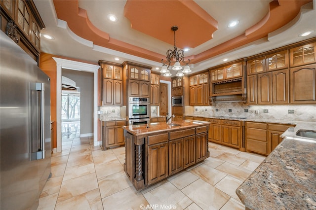 kitchen with stainless steel appliances, hanging light fixtures, a raised ceiling, and brown cabinets