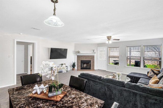 living room featuring baseboards, visible vents, ceiling fan, a tile fireplace, and tile patterned floors