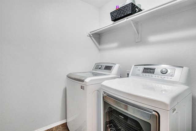 clothes washing area with washer and dryer, baseboards, and laundry area