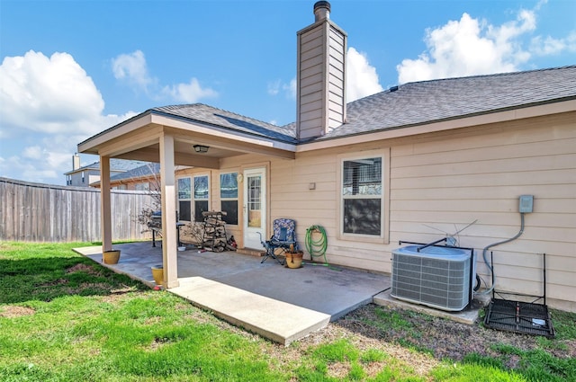 rear view of property featuring cooling unit, a patio, a lawn, and fence