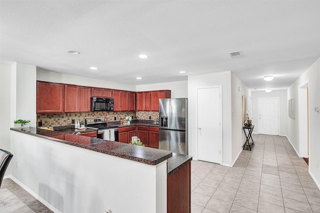 kitchen featuring dark countertops, a peninsula, stainless steel appliances, and tasteful backsplash