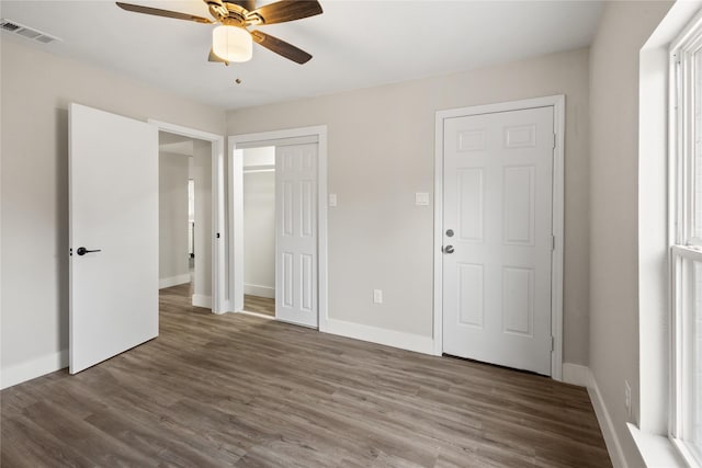 unfurnished bedroom featuring a closet, visible vents, baseboards, and wood finished floors