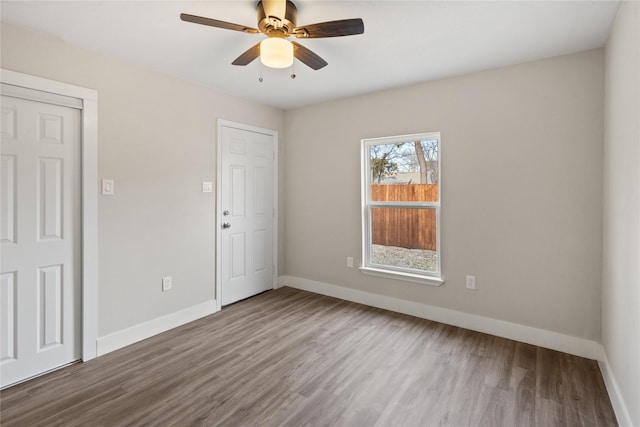 unfurnished room featuring ceiling fan, wood finished floors, and baseboards