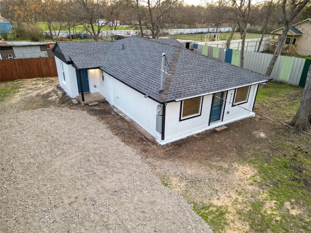 exterior space featuring a shingled roof and fence