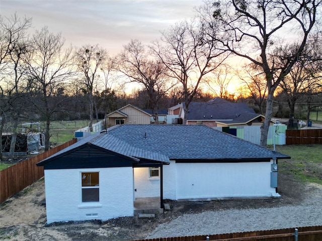 view of front of property with brick siding, roof with shingles, and fence