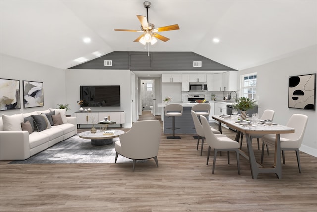 living room with light wood finished floors, ceiling fan, and vaulted ceiling