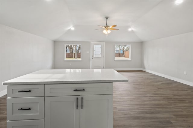 kitchen featuring a center island, lofted ceiling, dark wood-type flooring, open floor plan, and baseboards