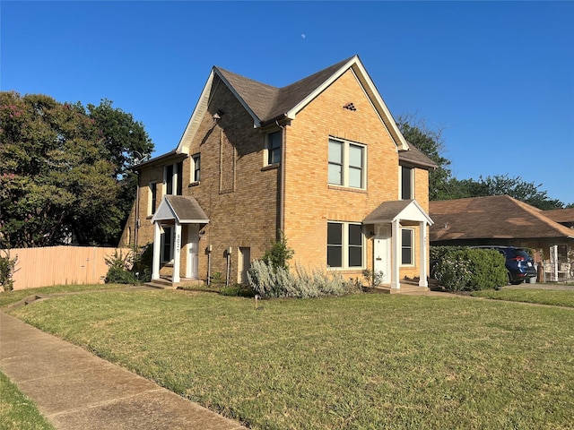 view of front facade with a front yard, fence, and brick siding