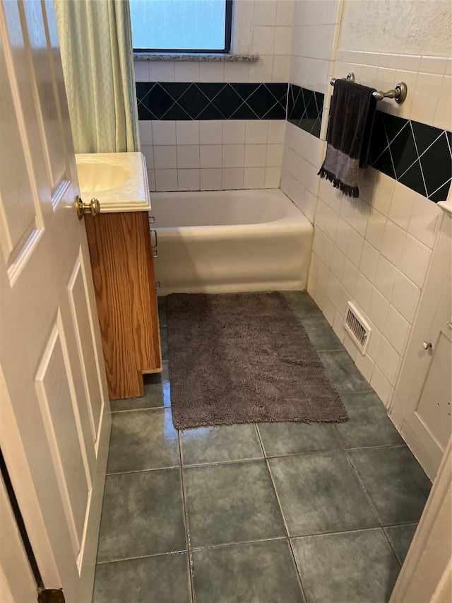 bathroom featuring shower / tub combination, tile patterned flooring, a sink, visible vents, and tile walls