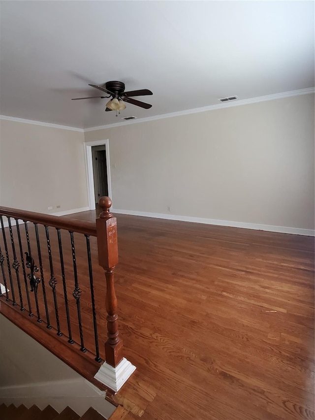 spare room featuring baseboards, visible vents, wood finished floors, and ornamental molding