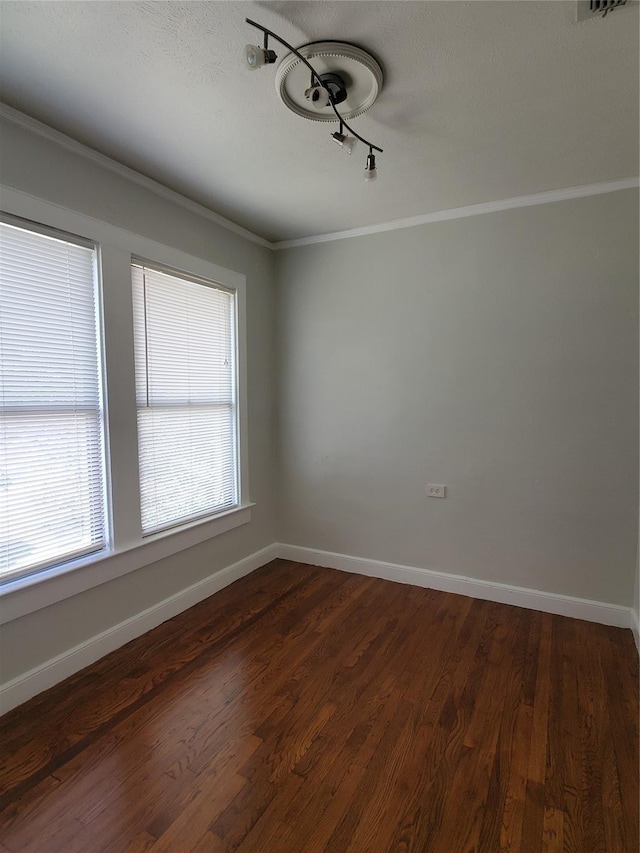 spare room with crown molding, baseboards, and dark wood-type flooring