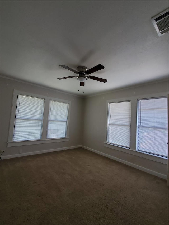 empty room with carpet flooring, crown molding, visible vents, and baseboards