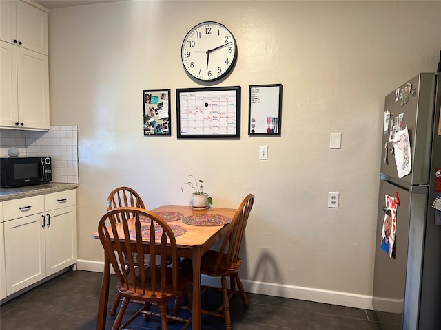 dining space featuring dark tile patterned flooring and baseboards