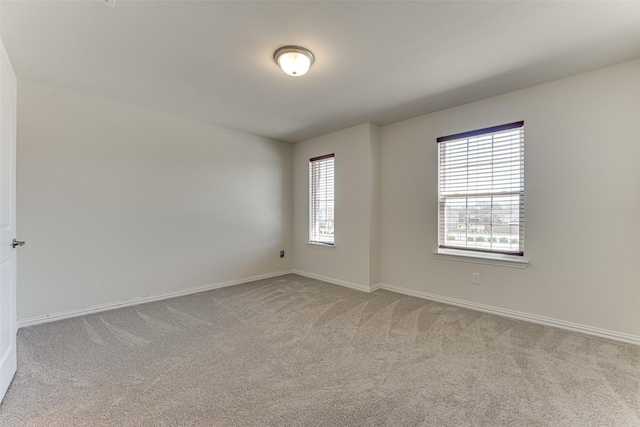 spare room featuring carpet flooring and baseboards