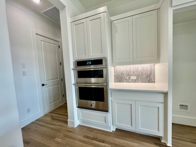 kitchen with visible vents, light countertops, stainless steel double oven, and wood finished floors