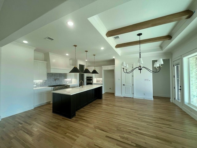 kitchen with a sink, visible vents, light countertops, custom exhaust hood, and beam ceiling