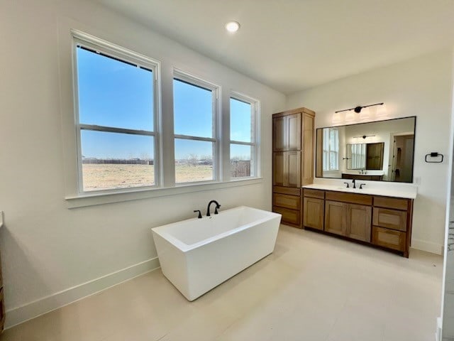 bathroom with recessed lighting, a freestanding tub, vanity, and baseboards