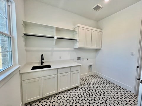 clothes washing area featuring hookup for a washing machine, cabinet space, a sink, and baseboards