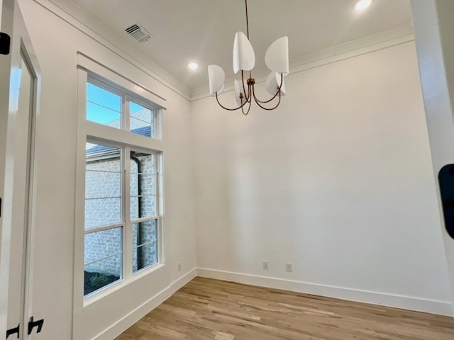 unfurnished dining area featuring baseboards, light wood-type flooring, visible vents, and an inviting chandelier