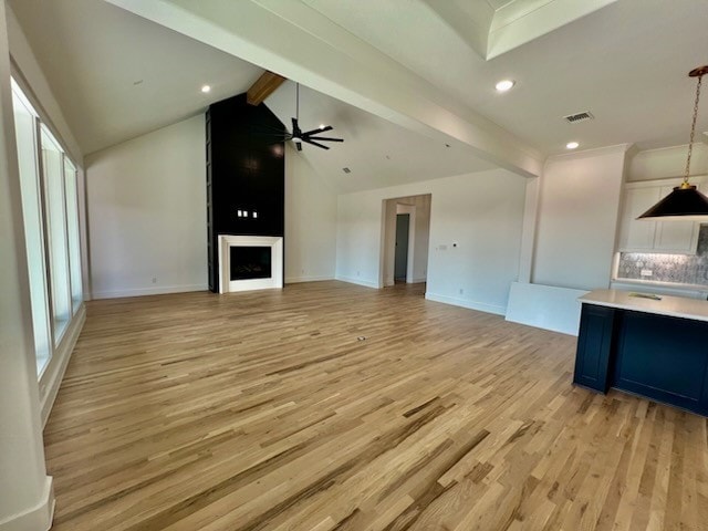 unfurnished living room featuring visible vents, light wood-style flooring, lofted ceiling with beams, a large fireplace, and ceiling fan