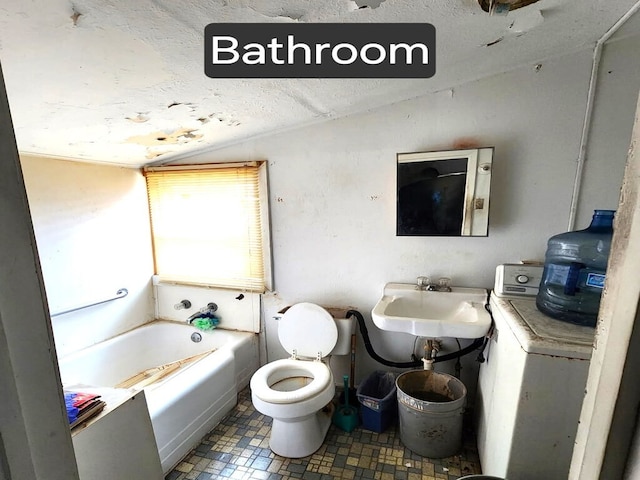 full bath with washer / dryer, toilet, a bath, vaulted ceiling, and a sink