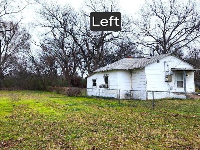 view of side of home with fence and a yard