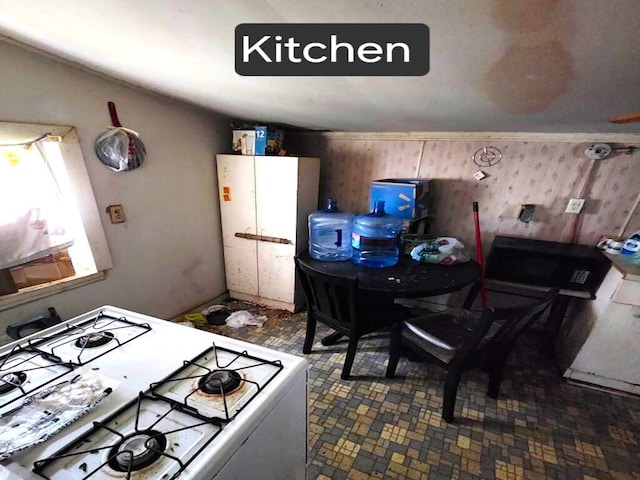 kitchen with white gas range and wooden walls