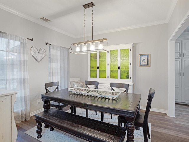 dining area featuring plenty of natural light, visible vents, wood finished floors, and ornamental molding