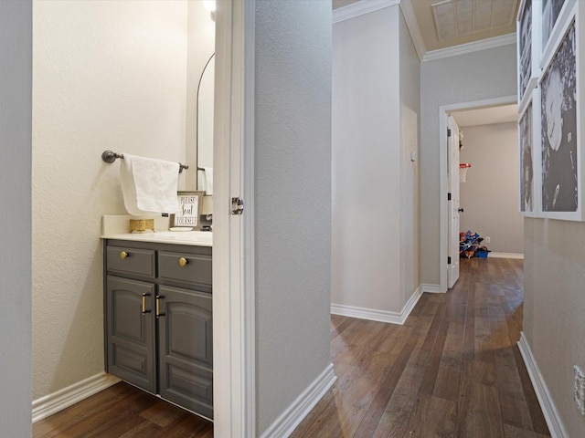 bathroom with wood-type flooring, ornamental molding, baseboards, and vanity