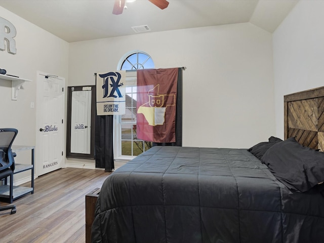 bedroom featuring vaulted ceiling, wood finished floors, visible vents, and a ceiling fan