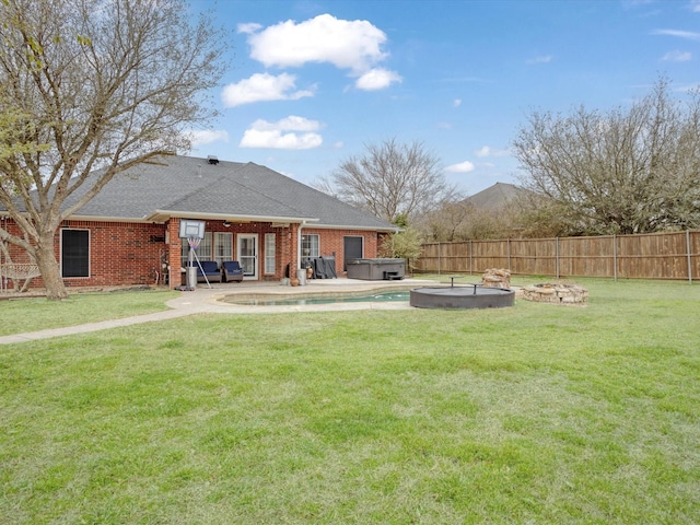 rear view of house with a fire pit, a fenced backyard, a yard, and a hot tub