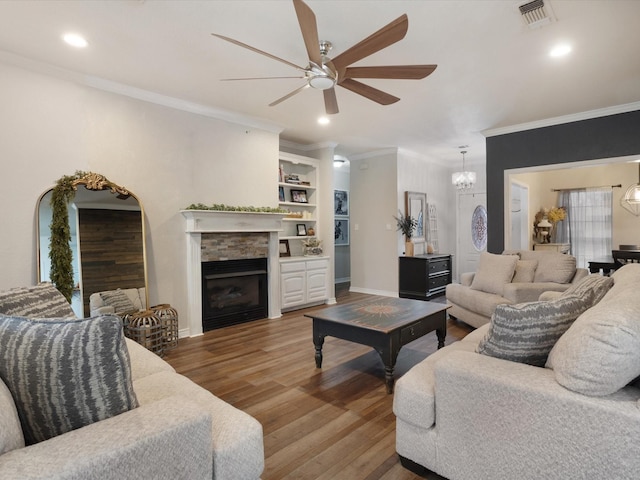 living room with a fireplace, wood finished floors, visible vents, baseboards, and crown molding