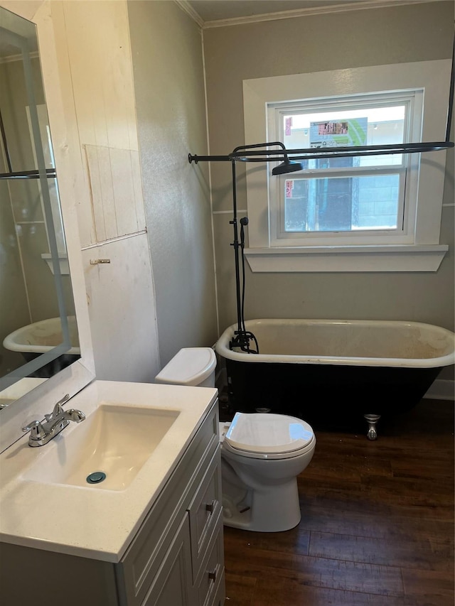 full bath with toilet, a freestanding bath, hardwood / wood-style floors, and vanity