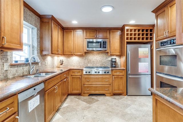 kitchen with appliances with stainless steel finishes, brown cabinets, a sink, and backsplash