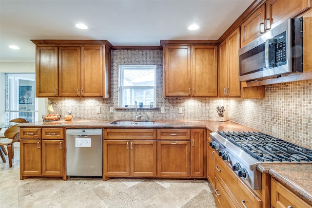 kitchen featuring stainless steel appliances, brown cabinets, a sink, and backsplash