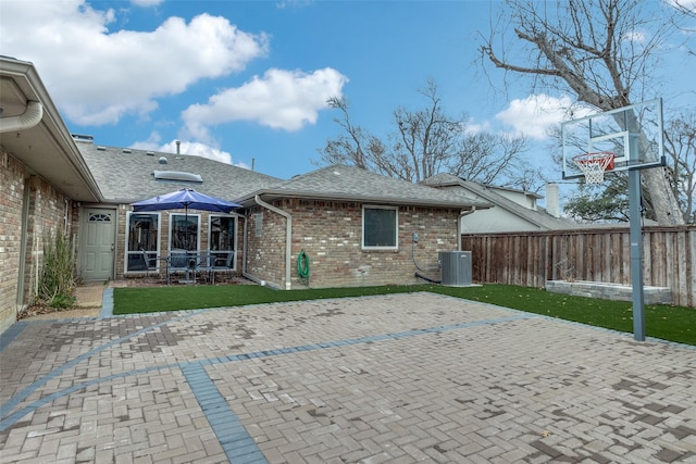 rear view of house with brick siding, a yard, a patio, central air condition unit, and fence