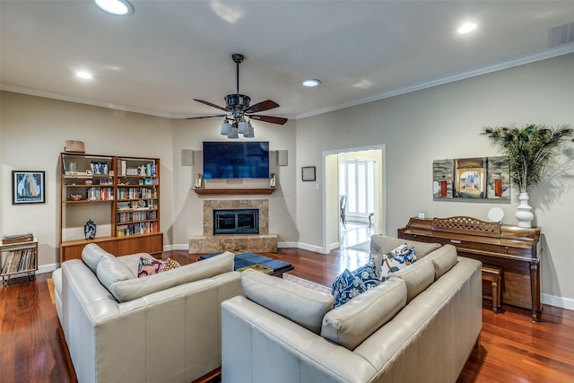 living area with dark wood-style floors, a tile fireplace, ornamental molding, and recessed lighting