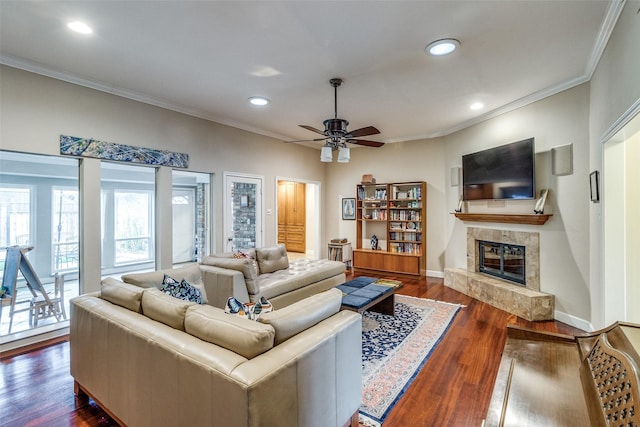 living room with a tile fireplace, recessed lighting, baseboards, ornamental molding, and dark wood finished floors