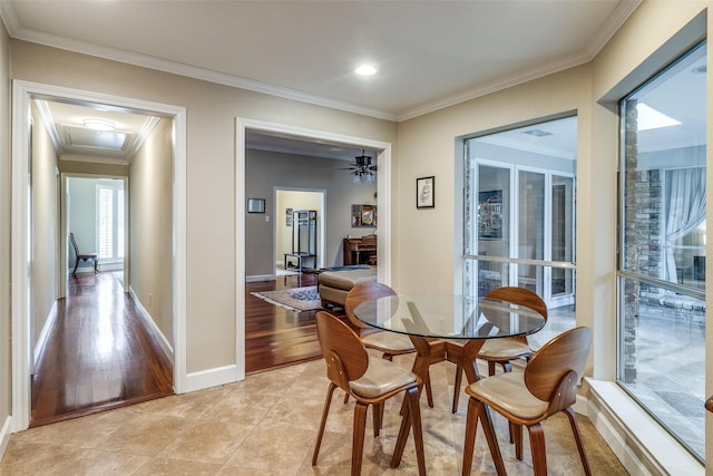 dining room featuring a fireplace, light tile patterned flooring, crown molding, and baseboards